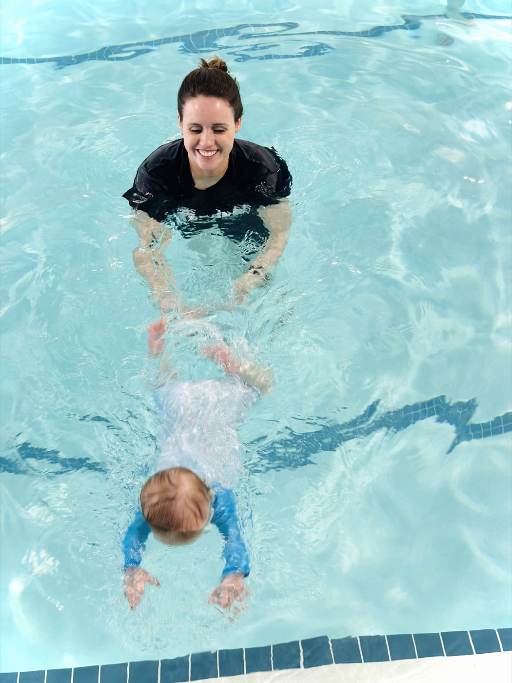The instructor guiding a baby to glide through the water
