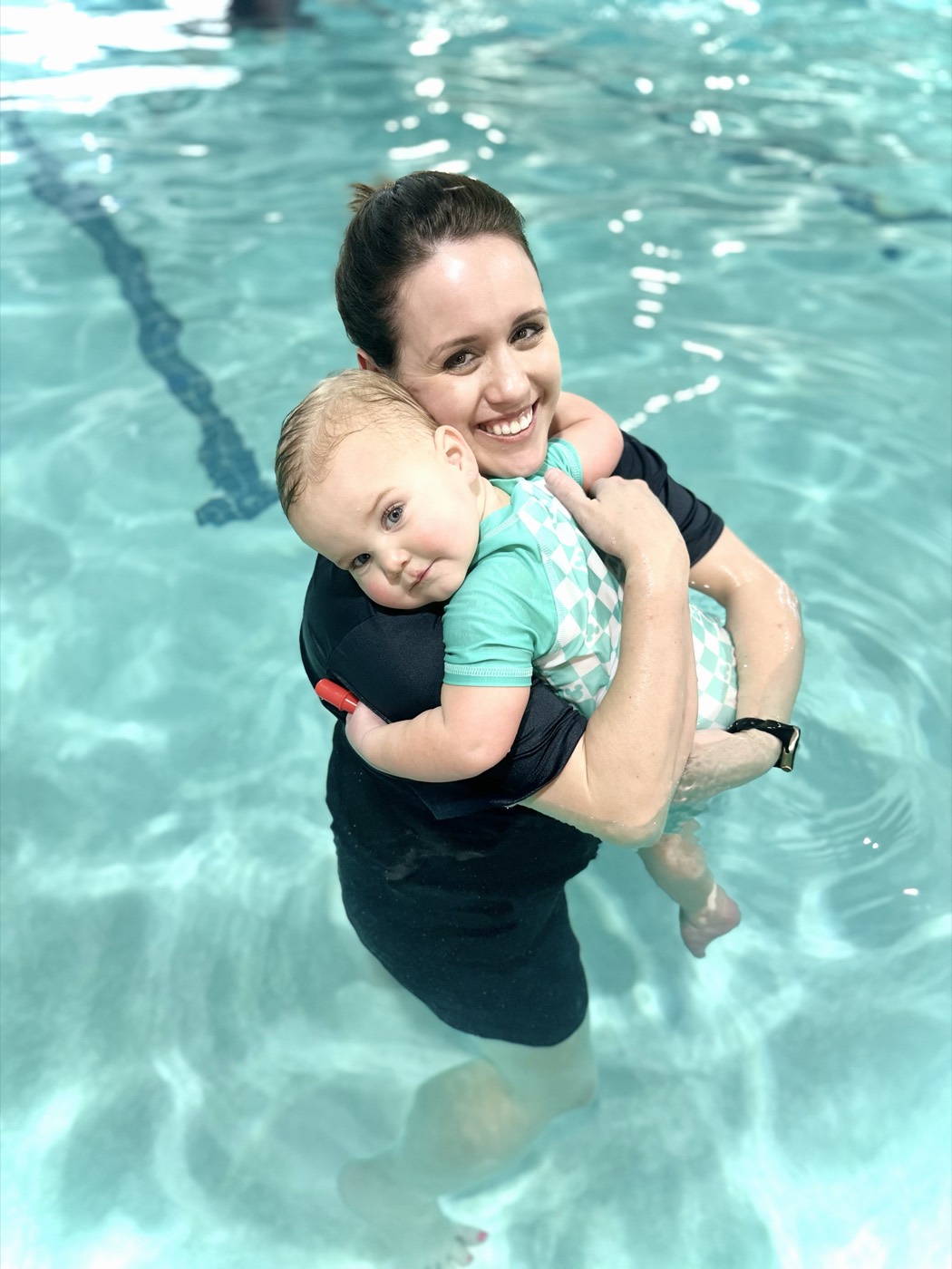 Katrina hugging a happy toddler in the pool