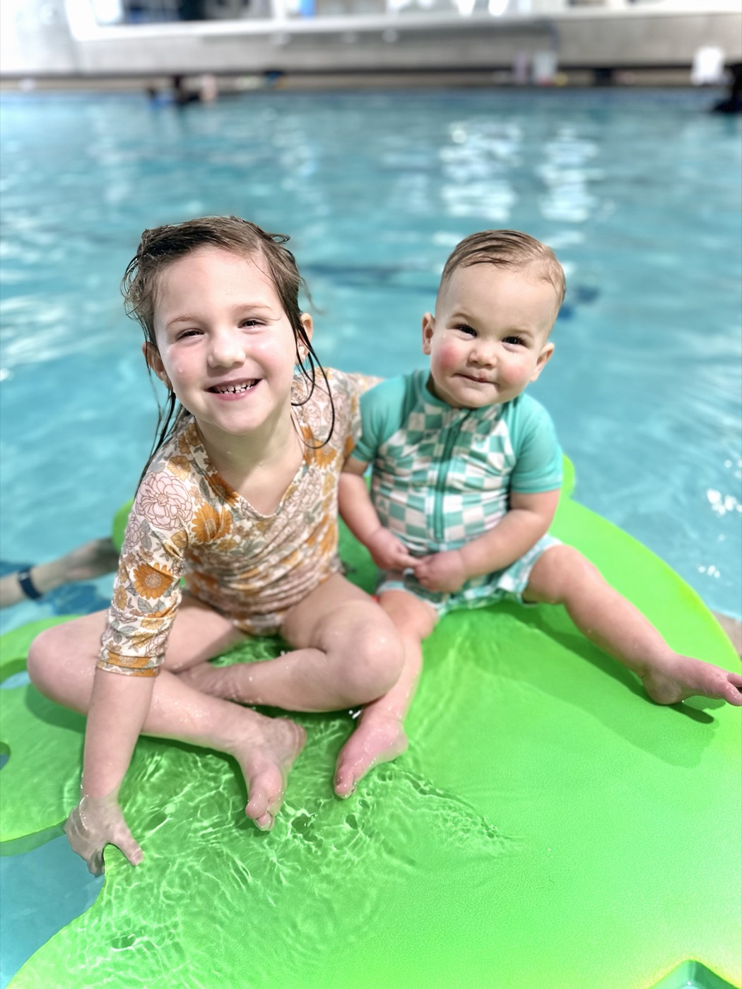 Two happy kids sitting on a pool float together